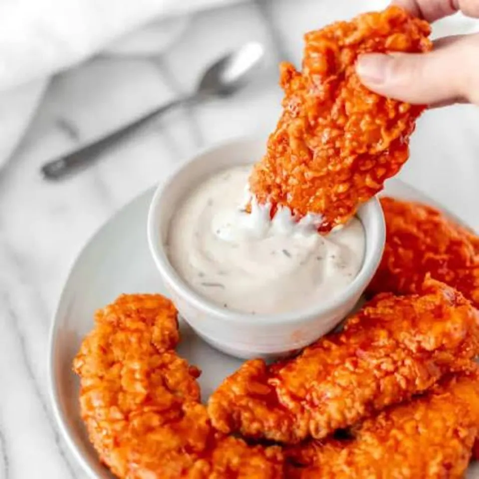 Crispy chicken tenders with a cup of white sauce